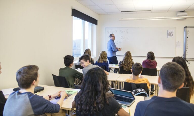 Schoolchildren (12-13, 14-15) listening to teacher in classroom