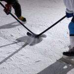 opponents holding hockey sticks beside each other